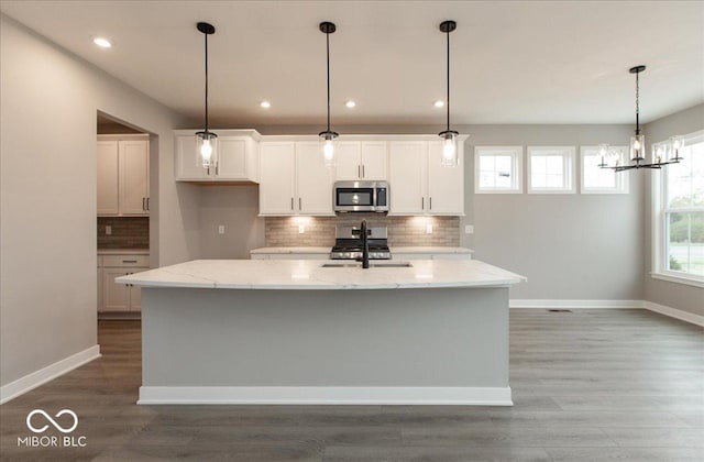 6973 Oakdale Ln, Avon, IN 46123 - kitchen featuring white cabinets, an island with sink, light stone counters, tasteful backsplash, and appliances with stainless steel finishes