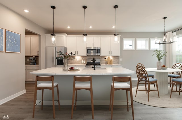 6973 Oakdale Ln, Avon, IN 46123 - kitchen with a sink, a center island with sink, decorative backsplash, appliances with stainless steel finishes, and a breakfast bar area