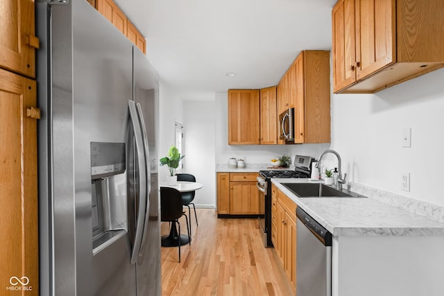 kitchen featuring light wood-type flooring, sink, and appliances with stainless steel finishes