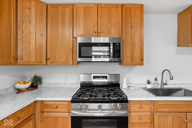 kitchen featuring light stone countertops, sink, and appliances with stainless steel finishes