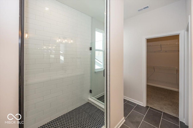 bathroom with tile patterned flooring, a shower stall, a spacious closet, and baseboards