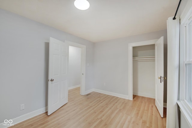 unfurnished bedroom with light hardwood / wood-style flooring and a closet