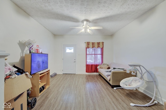 interior space with ceiling fan, a textured ceiling, and light wood-type flooring