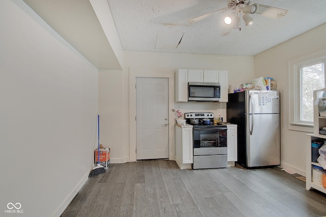 kitchen featuring white cabinetry, light hardwood / wood-style flooring, a textured ceiling, and appliances with stainless steel finishes