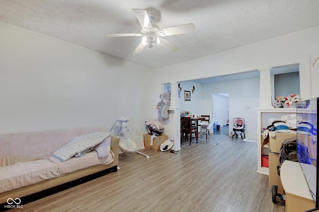 bedroom with ceiling fan, light hardwood / wood-style flooring, a textured ceiling, and ornate columns