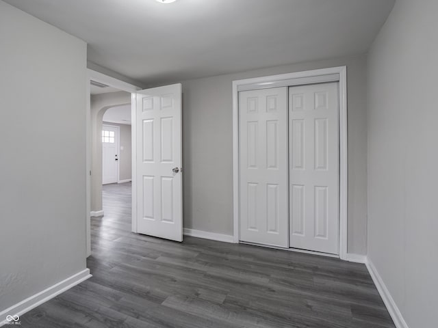 unfurnished bedroom featuring dark wood-type flooring and a closet