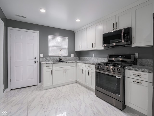 kitchen with light stone countertops, sink, white cabinetry, and stainless steel appliances