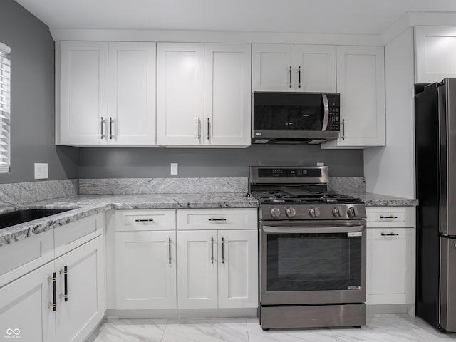 kitchen featuring white cabinetry, sink, light stone countertops, and appliances with stainless steel finishes