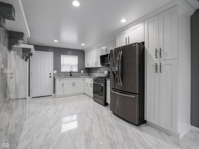 kitchen with white cabinets, light stone counters, sink, and appliances with stainless steel finishes