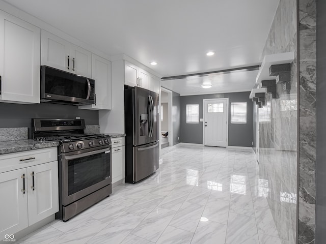 kitchen featuring white cabinetry, appliances with stainless steel finishes, and dark stone counters