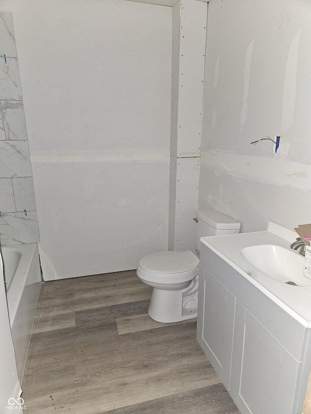 bathroom featuring a bathing tub, hardwood / wood-style floors, vanity, and toilet