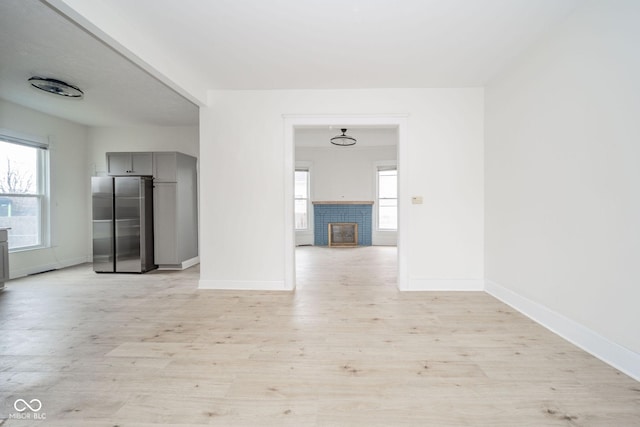 spare room featuring a fireplace and light hardwood / wood-style floors