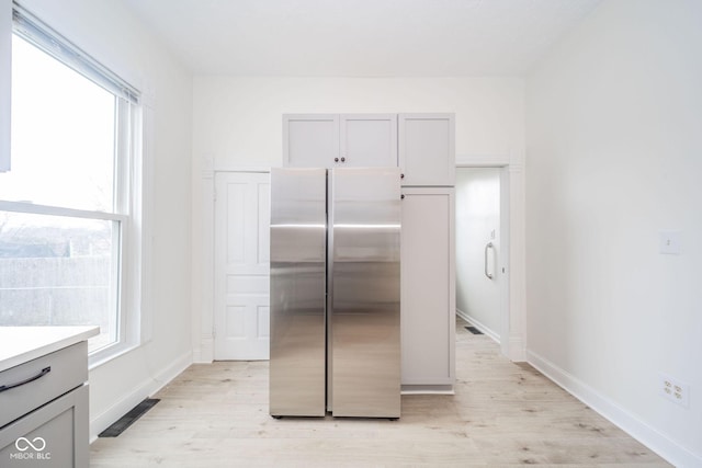 kitchen with stainless steel fridge, light wood-type flooring, and gray cabinets