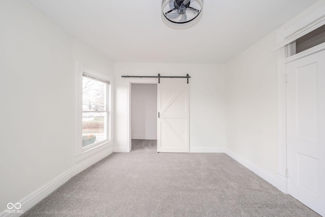 unfurnished bedroom with carpet, a barn door, and a closet