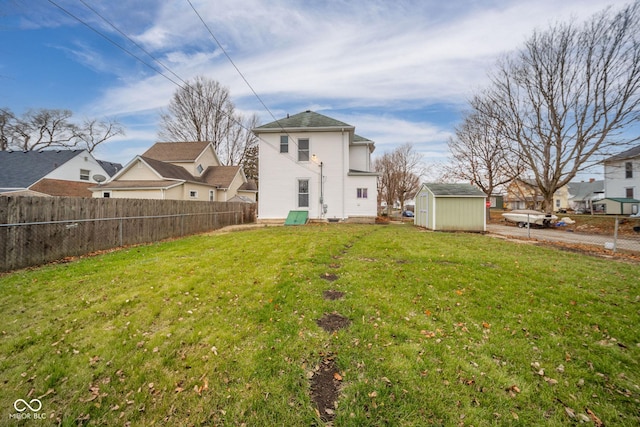 back of house with a lawn and a storage unit