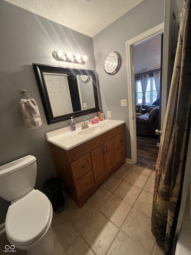 bathroom featuring tile patterned flooring, vanity, a textured ceiling, and toilet