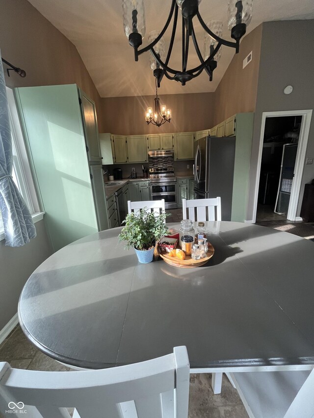 kitchen with appliances with stainless steel finishes, lofted ceiling, a notable chandelier, and sink