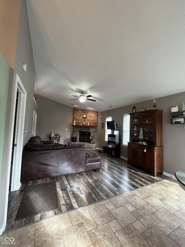 unfurnished living room featuring hardwood / wood-style floors, a large fireplace, a textured ceiling, and ceiling fan