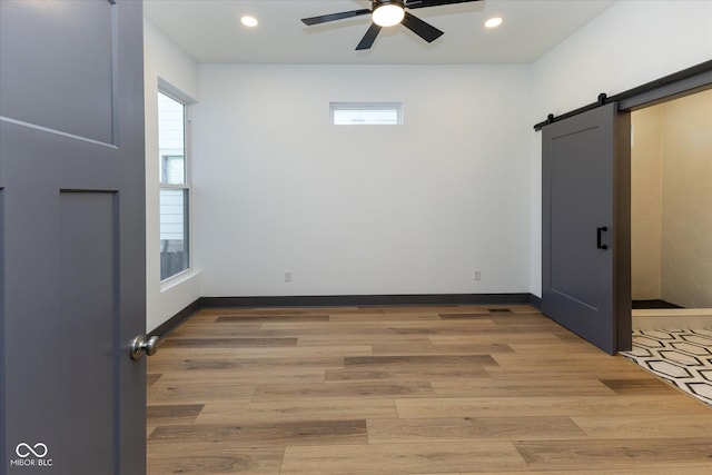 interior space featuring ceiling fan, a barn door, and wood-type flooring