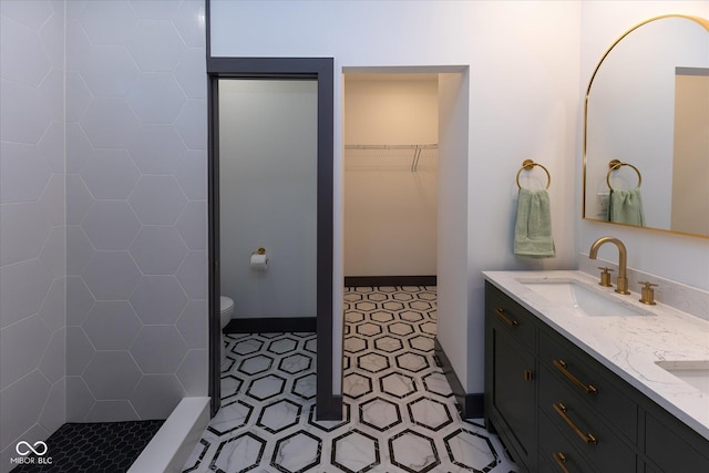 bathroom with a tile shower, vanity, and toilet