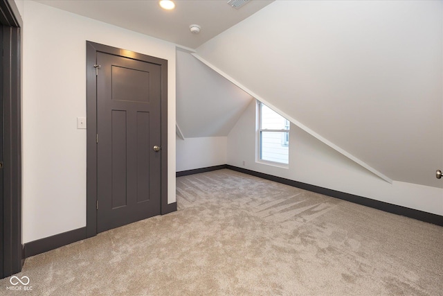 bonus room with light carpet and vaulted ceiling