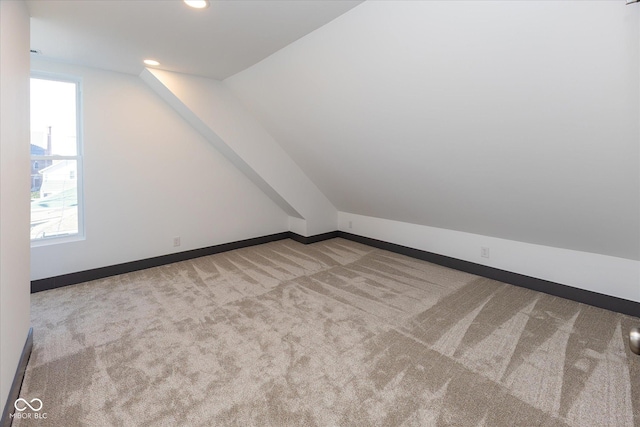 additional living space featuring light colored carpet and lofted ceiling