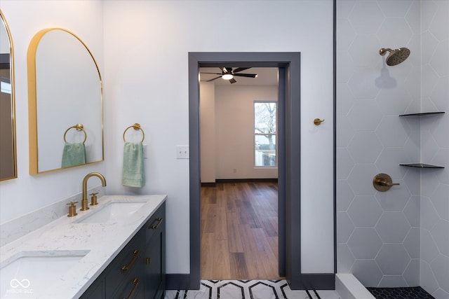 bathroom with hardwood / wood-style flooring, vanity, ceiling fan, and tiled shower