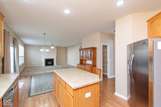 kitchen featuring pendant lighting, light brown cabinets, light hardwood / wood-style floors, a kitchen island, and stainless steel appliances