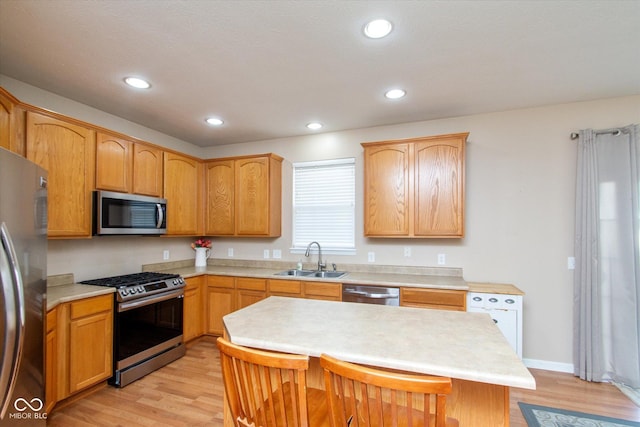 kitchen with sink, a center island, stainless steel appliances, a breakfast bar area, and light wood-type flooring