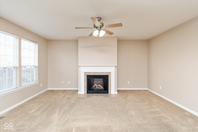 unfurnished living room with a tile fireplace, light colored carpet, and ceiling fan