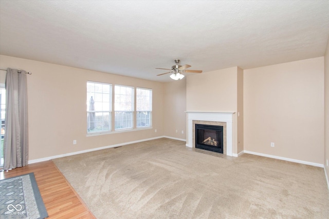 living room featuring ceiling fan, a textured ceiling, a tile fireplace, and light hardwood / wood-style flooring