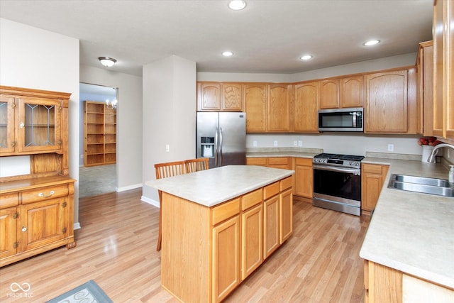 kitchen with a center island, sink, appliances with stainless steel finishes, and light hardwood / wood-style flooring