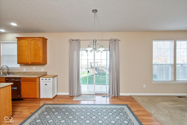 kitchen with a chandelier, dishwasher, pendant lighting, and light hardwood / wood-style flooring