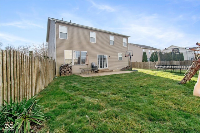 back of property featuring a yard, a patio, and a trampoline