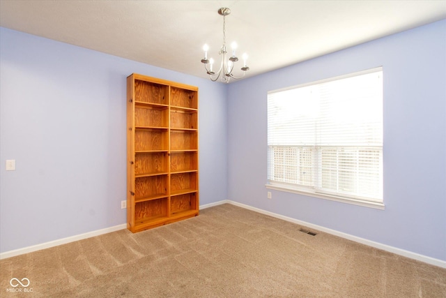 spare room with a chandelier and carpet