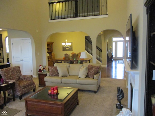 carpeted living room featuring a towering ceiling and a chandelier