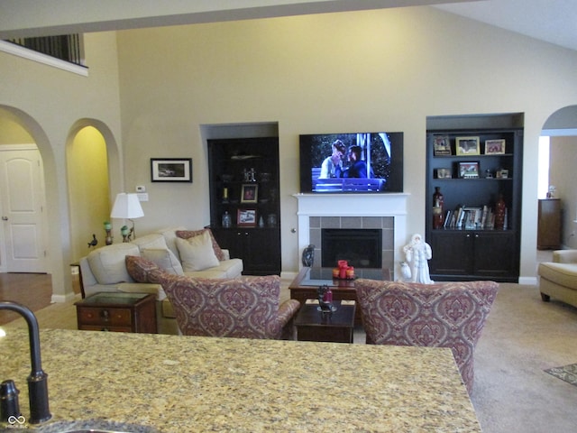 carpeted living room with high vaulted ceiling and a tile fireplace