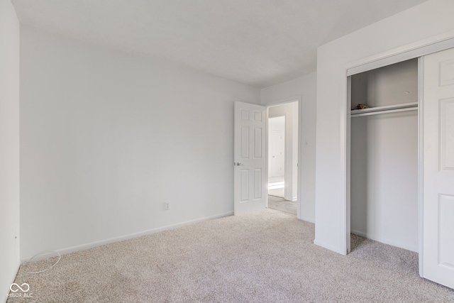 unfurnished bedroom with light carpet and a closet