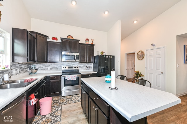 kitchen with backsplash, stainless steel appliances, sink, a center island, and light hardwood / wood-style floors