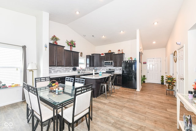 kitchen with black fridge with ice dispenser, light wood-type flooring, a center island, and dark brown cabinets