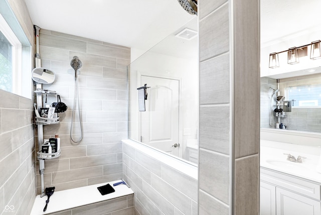 bathroom with vanity, a tile shower, and tile walls