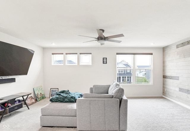 living room with ceiling fan, light colored carpet, and wooden walls