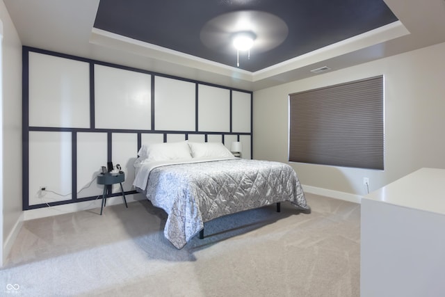 carpeted bedroom with a raised ceiling