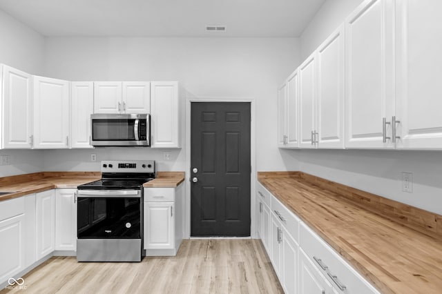 kitchen with white cabinets, wood counters, light wood-type flooring, and stainless steel appliances