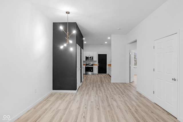 interior space with pendant lighting, light hardwood / wood-style flooring, appliances with stainless steel finishes, white cabinetry, and a chandelier