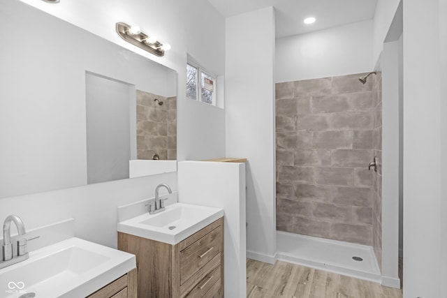 bathroom featuring hardwood / wood-style flooring, vanity, and tiled shower