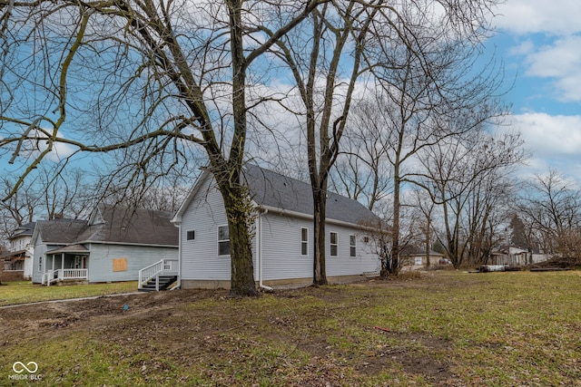 view of side of home featuring covered porch and a yard