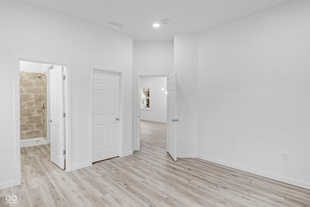 unfurnished bedroom featuring light hardwood / wood-style floors and connected bathroom