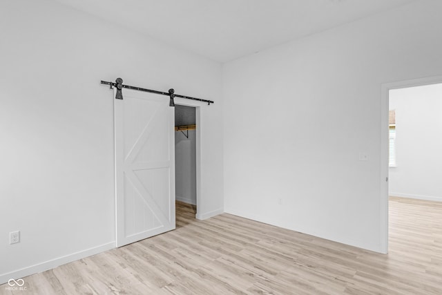 empty room with a barn door and light wood-type flooring