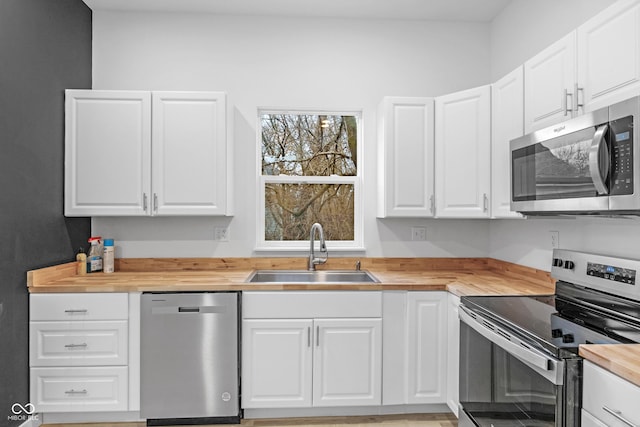 kitchen featuring butcher block counters, white cabinetry, sink, and appliances with stainless steel finishes